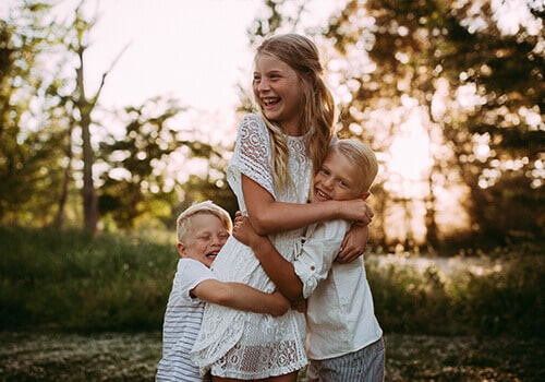 We offer compassionate care to families Dr. Minert's three children laughing and hugging in a field